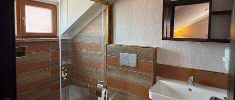 Un baño moderno con cabina de ducha de vidrio, inodoro, lavamanos y espejo.