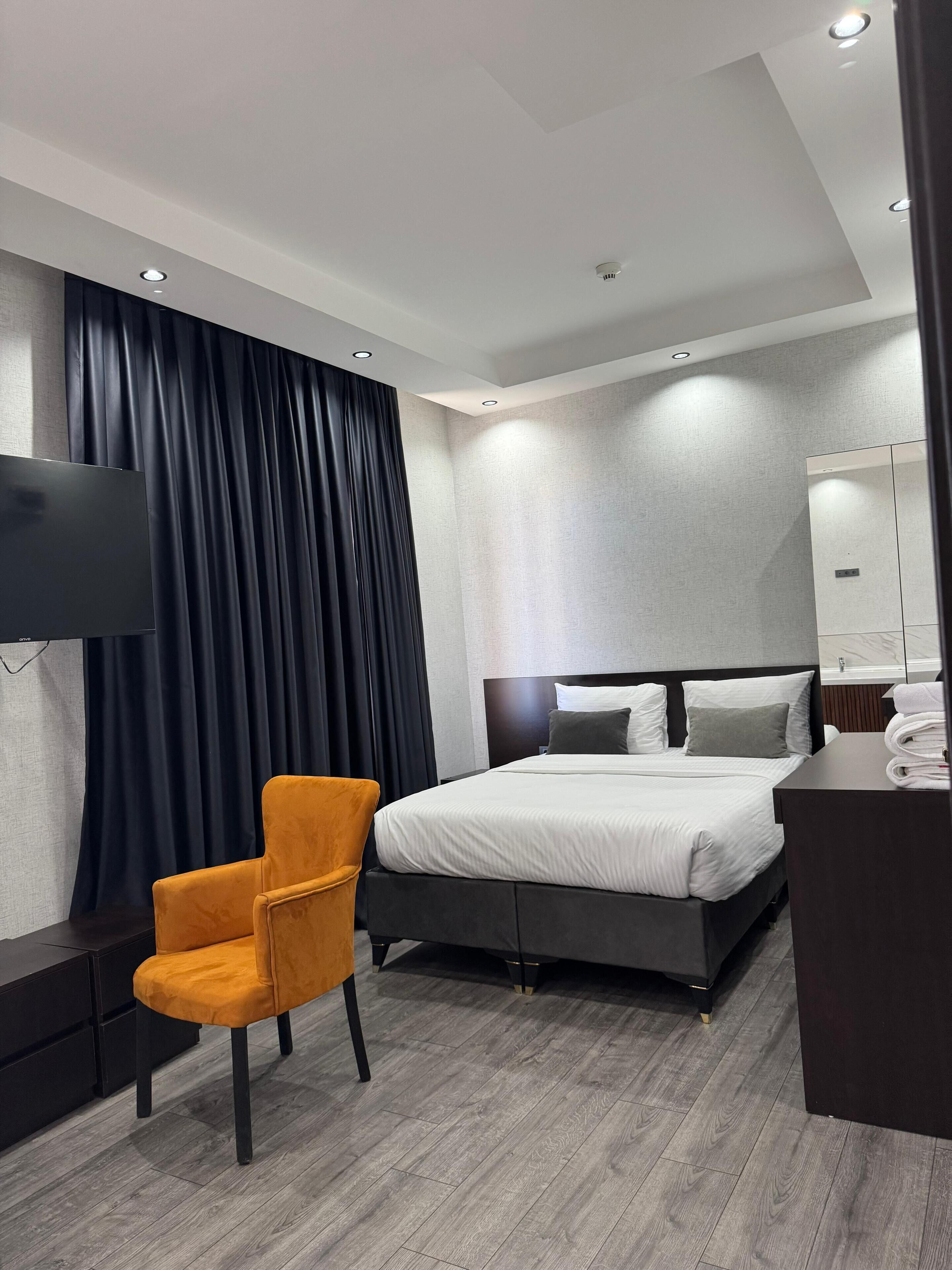 A modern hotel room with a bed, a TV, a desk, and a chair.
