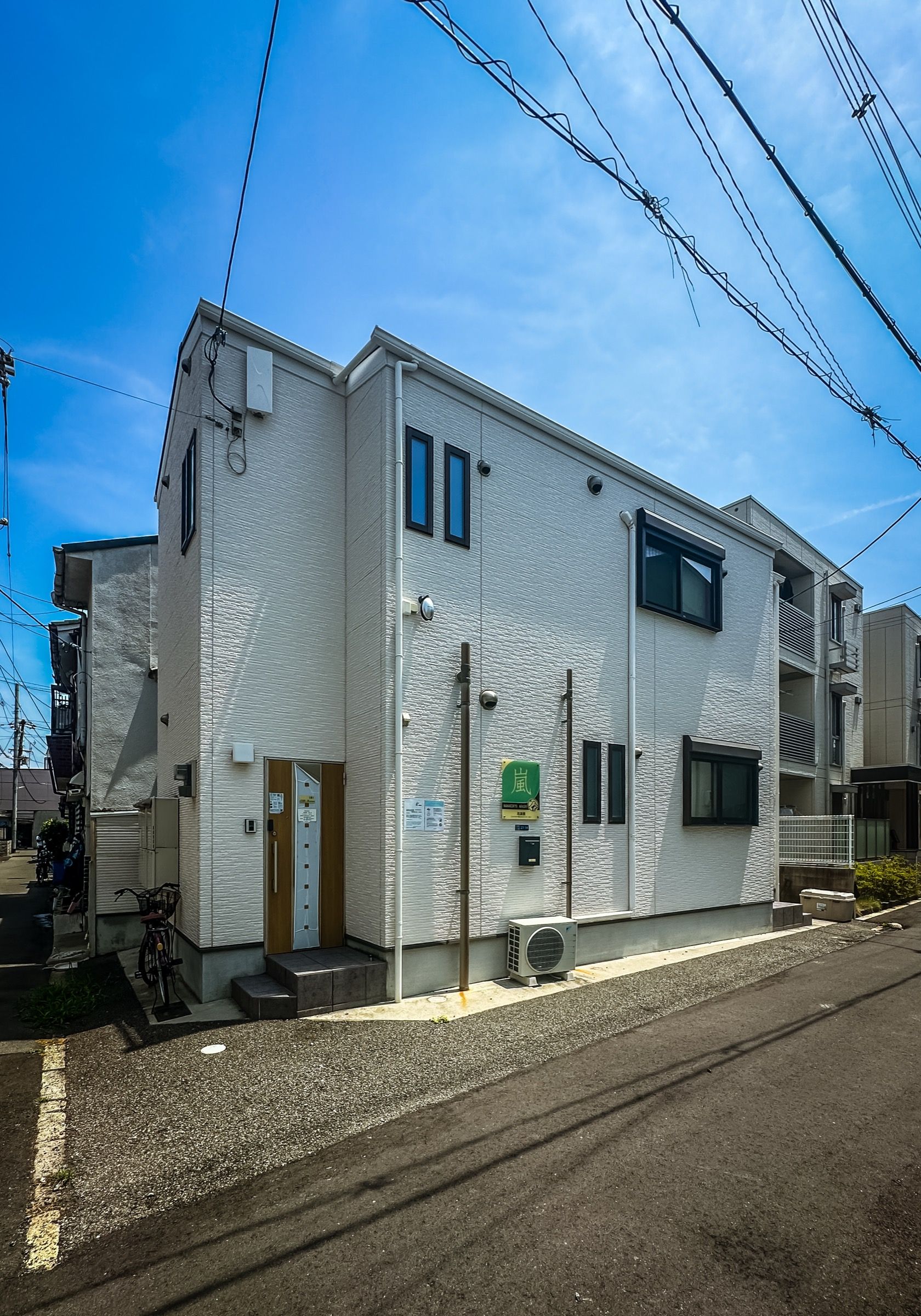 A two-story building with a white exterior, a front door, and a small balcony.