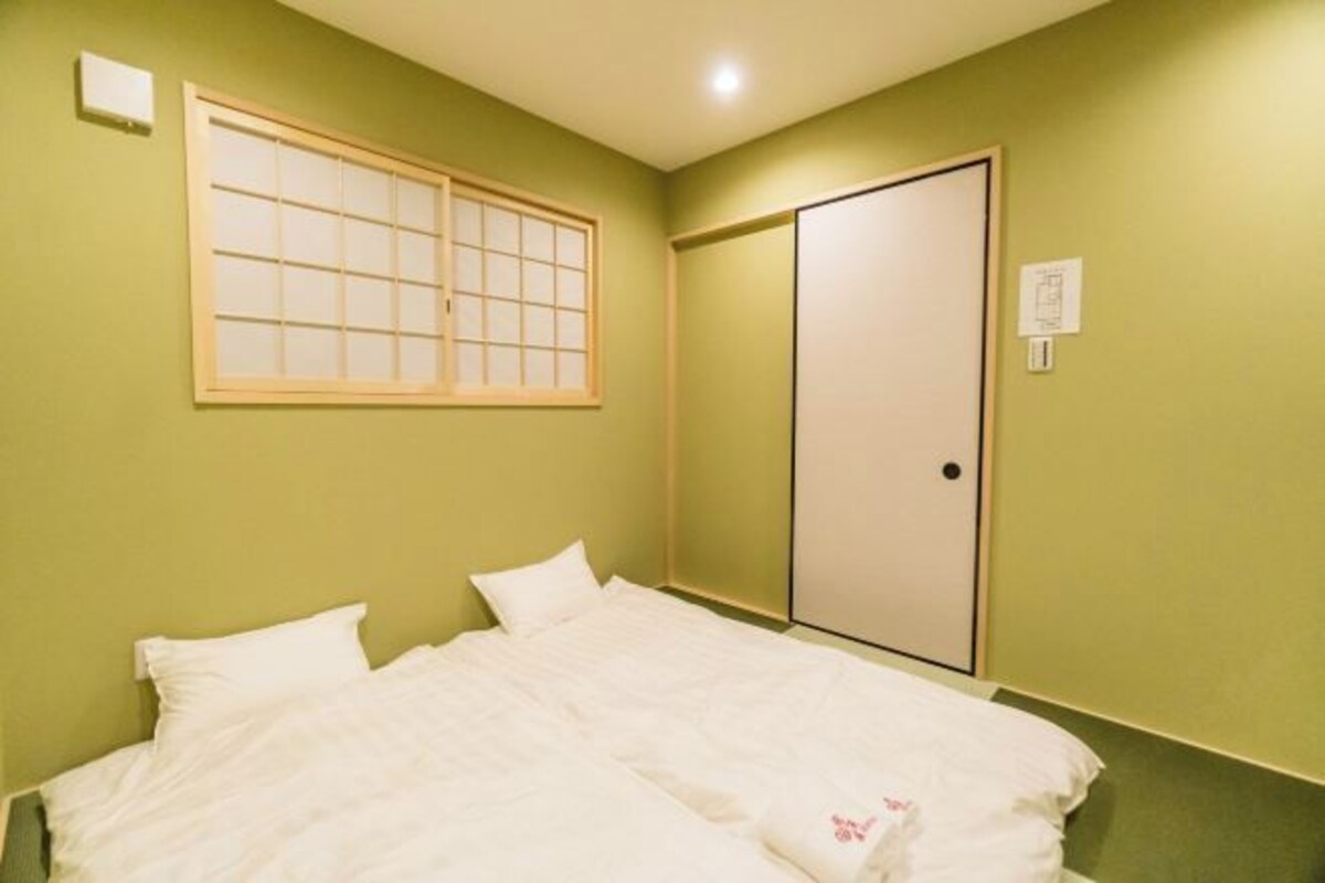 A room with a bed, a sliding door, and a window with a grid pattern.