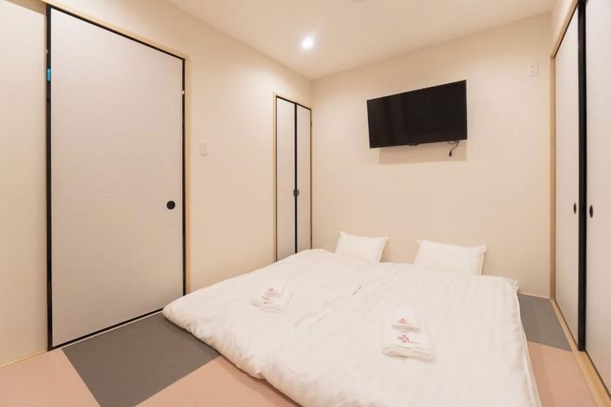 A bedroom with a bed, a television mounted on the wall, and sliding doors.