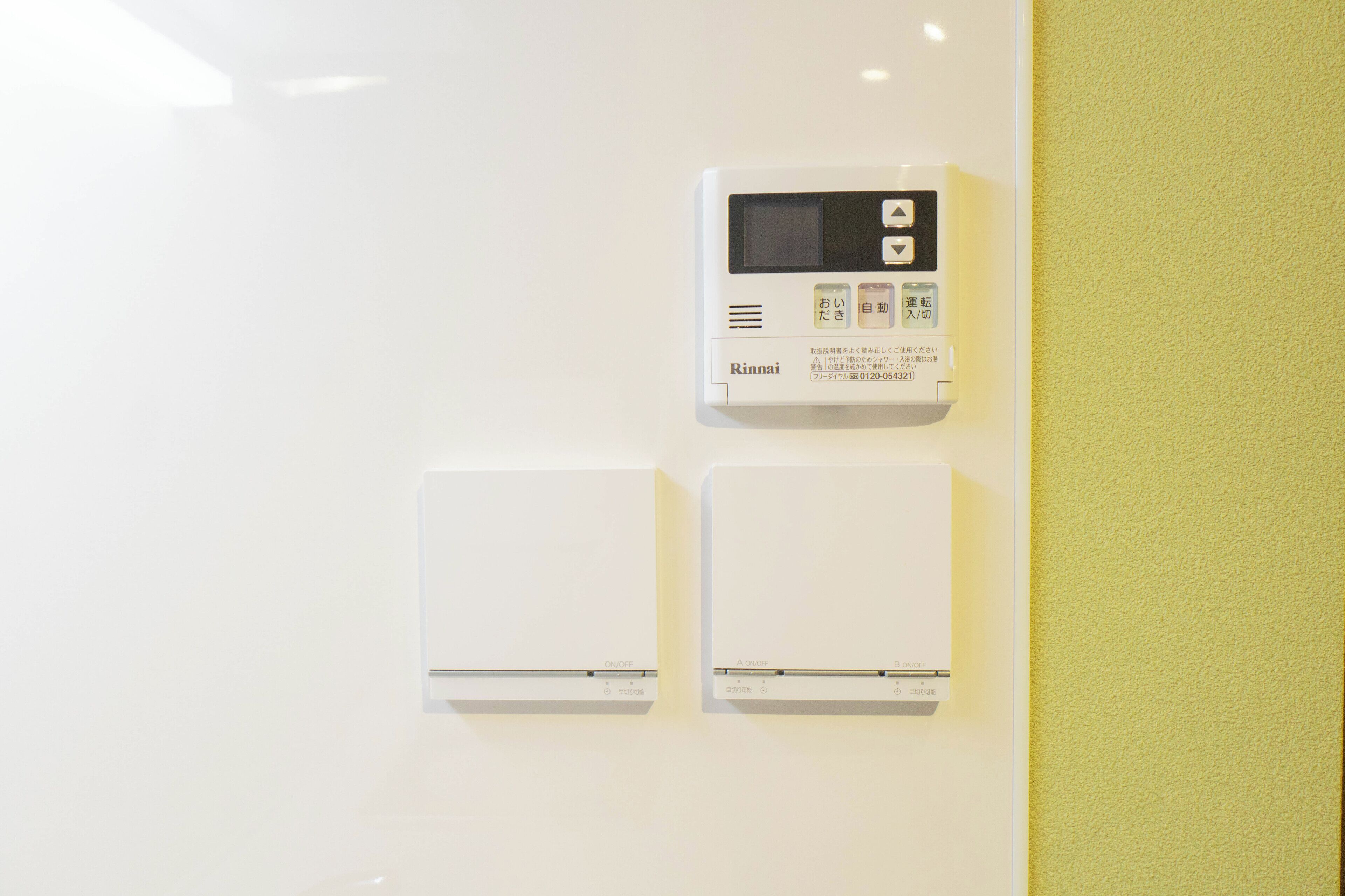 A wall-mounted control panel with a digital display and two white devices below it.
