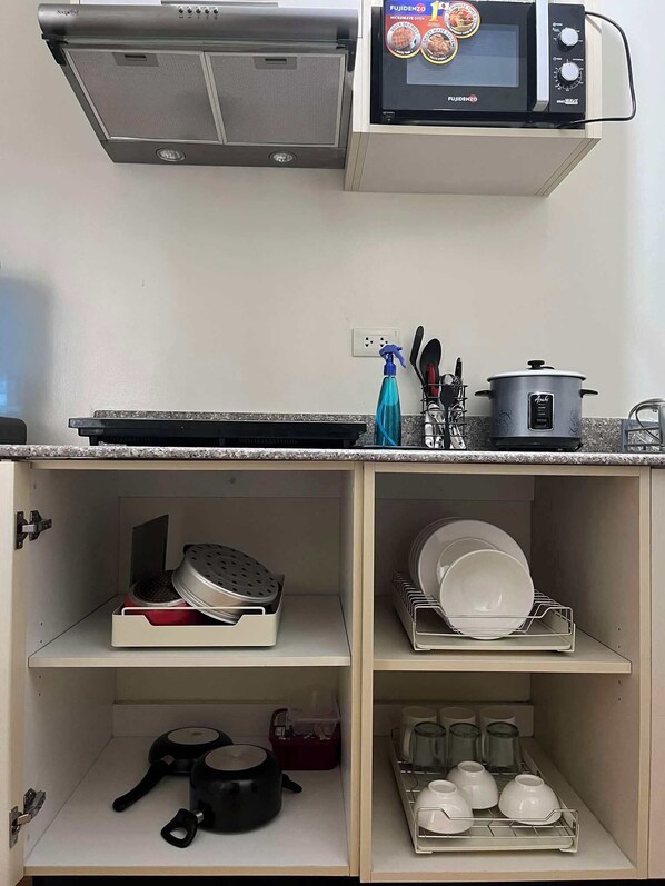 A kitchen with a microwave, stove, and various utensils.