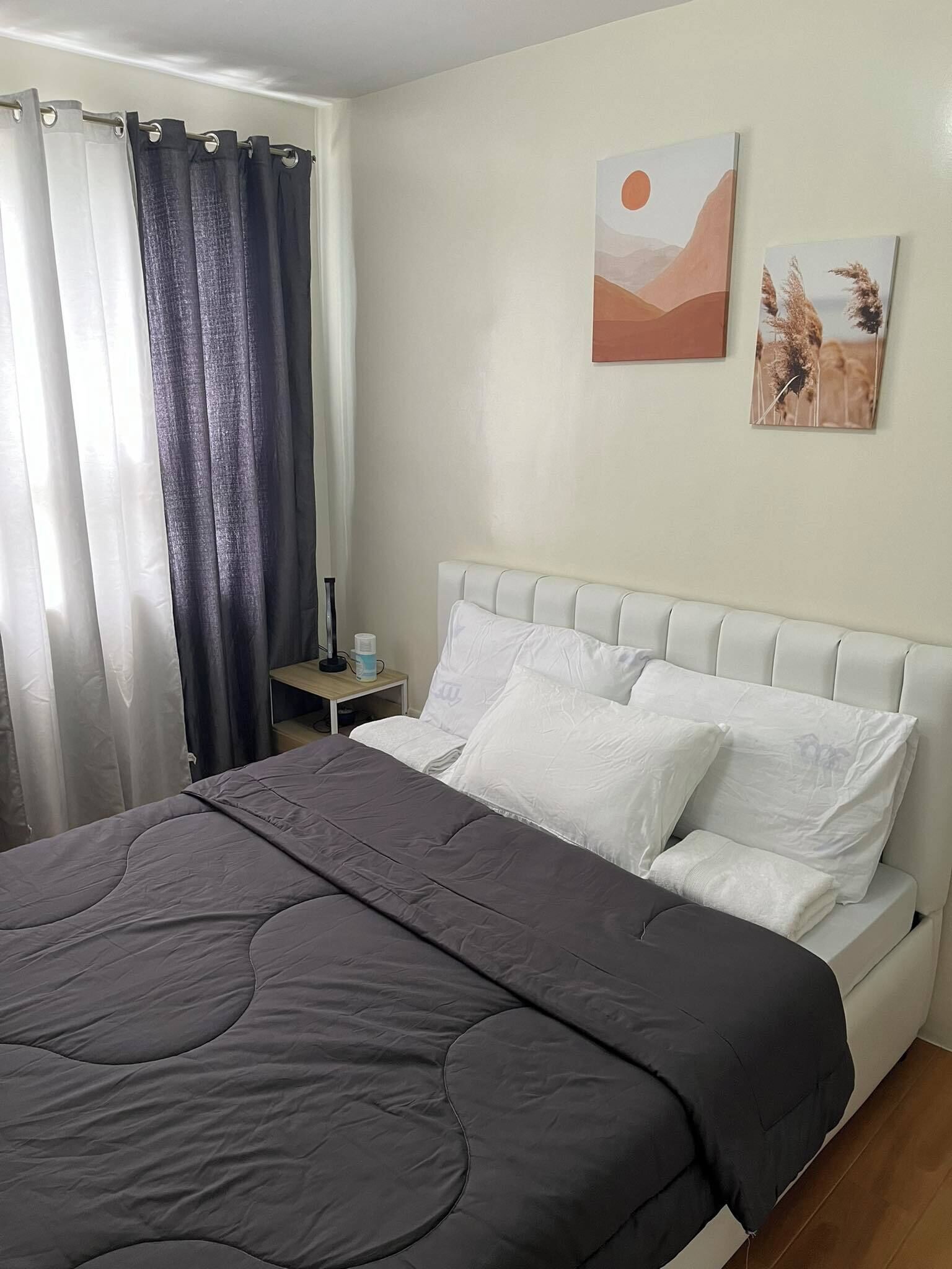 Ein Schlafzimmer mit einem Bett, einem Nachttisch, einer Lampe und zwei Wandbildern.