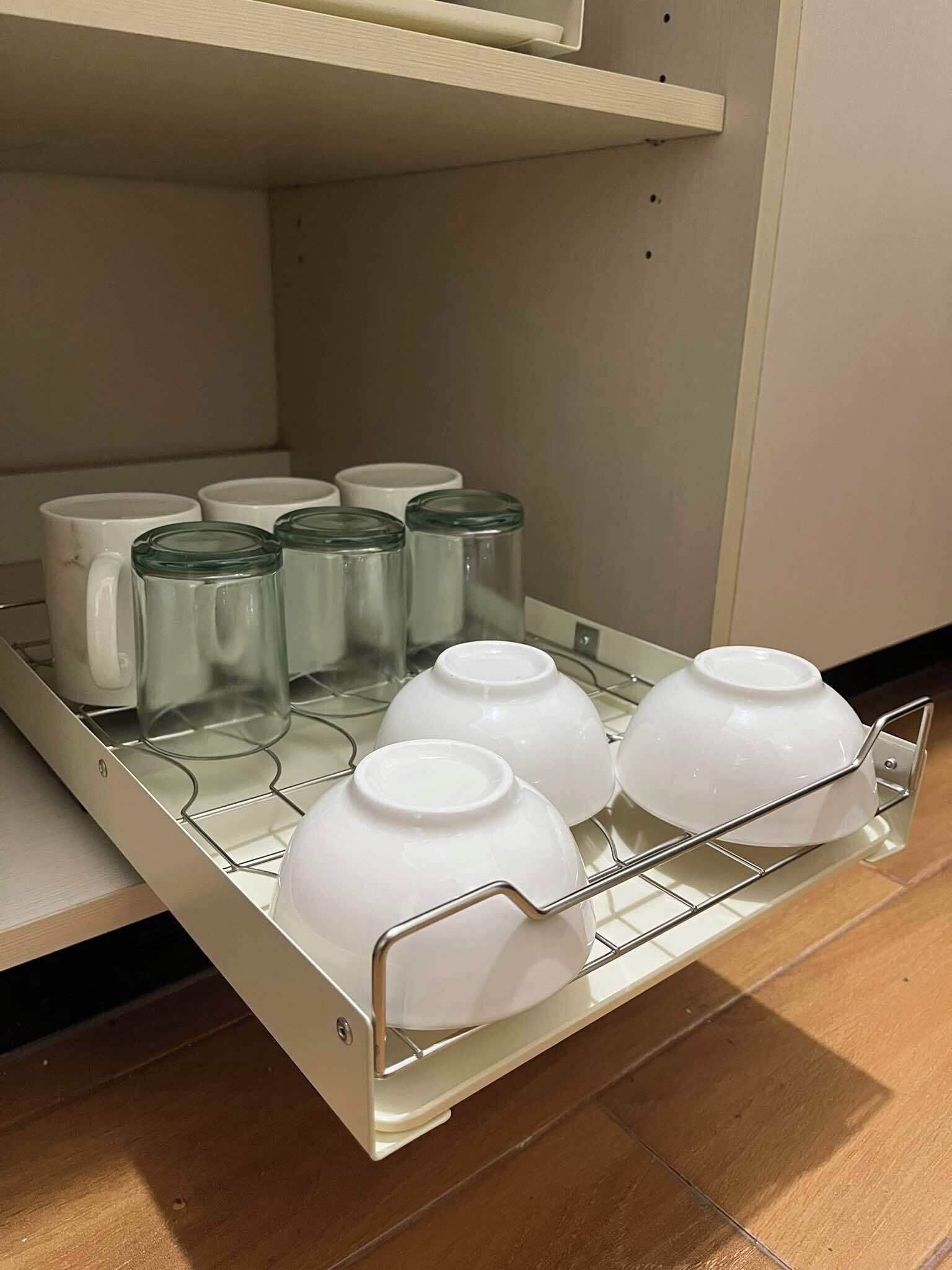 A kitchen area with a built-in shelf holding various kitchenware items.