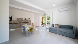 Un grand espace de vie comprenant une table à manger et des chaises, un canapé gris et une cuisine en arrière-plan.