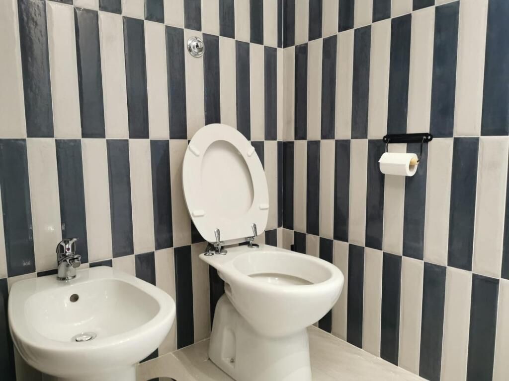 A bathroom with a bidet, a toilet, and a sink.