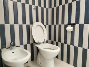 A bathroom with a bidet, a toilet, and a sink.