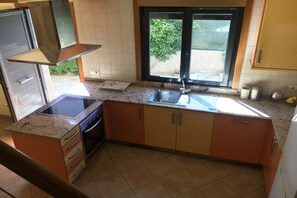A kitchen with a stove, sink, and window.