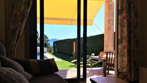 A room with a sliding glass door leading to an outdoor area with a yellow umbrella, a lawn, and a table with chairs. - Apartment in Cangas near Playa de Barra (Cangas do Morrazo)