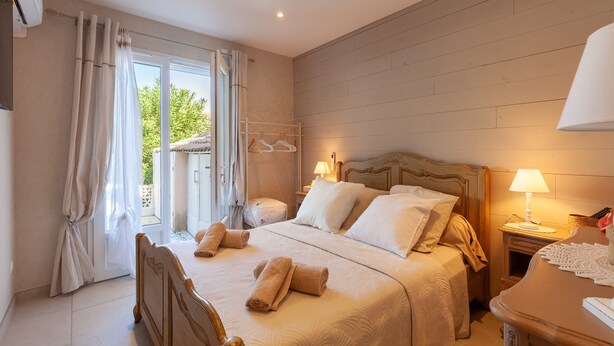 A bedroom with a bed, bedside tables, a lamp, and a view through the window. - Villa 'Soleil Et Douceur' with Private Pool, Wi-Fi and Air Conditioning (La Seyne-sur-Mer)