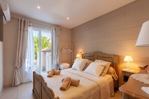 Ein Schlafzimmer mit einem Bett, Nachttischen, einer Lampe und Blick aus dem Fenster.