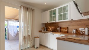 A kitchen with white cabinets, a wooden countertop, and a glass cabinet. - Villa 'Soleil Et Douceur' with Private Pool, Wi-Fi and Air Conditioning (La Seyne-sur-Mer)
