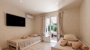 A room with two beds, a flat-screen TV, and a sliding glass door leading to an outdoor area. - Villa 'Soleil Et Douceur' with Private Pool, Wi-Fi and Air Conditioning (La Seyne-sur-Mer)