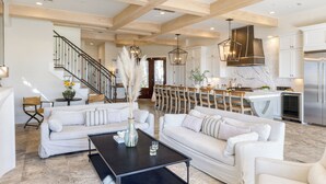 A spacious living area with a modern kitchen, wooden beams, and a staircase leading to another level. - Sleeps 48, 2 Homes w/ Private Beach Access | Bradley Circle Buyout by AvantStay (Hilton Head Island)