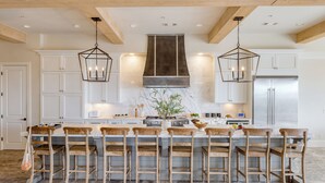 A kitchen with a large island, wooden chairs, and pendant lights. - Sleeps 48, 2 Homes w/ Private Beach Access | Bradley Circle Buyout by AvantStay (Hilton Head Island)