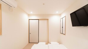 Un dormitorio con cama, armario, televisor y aire acondicionado.
