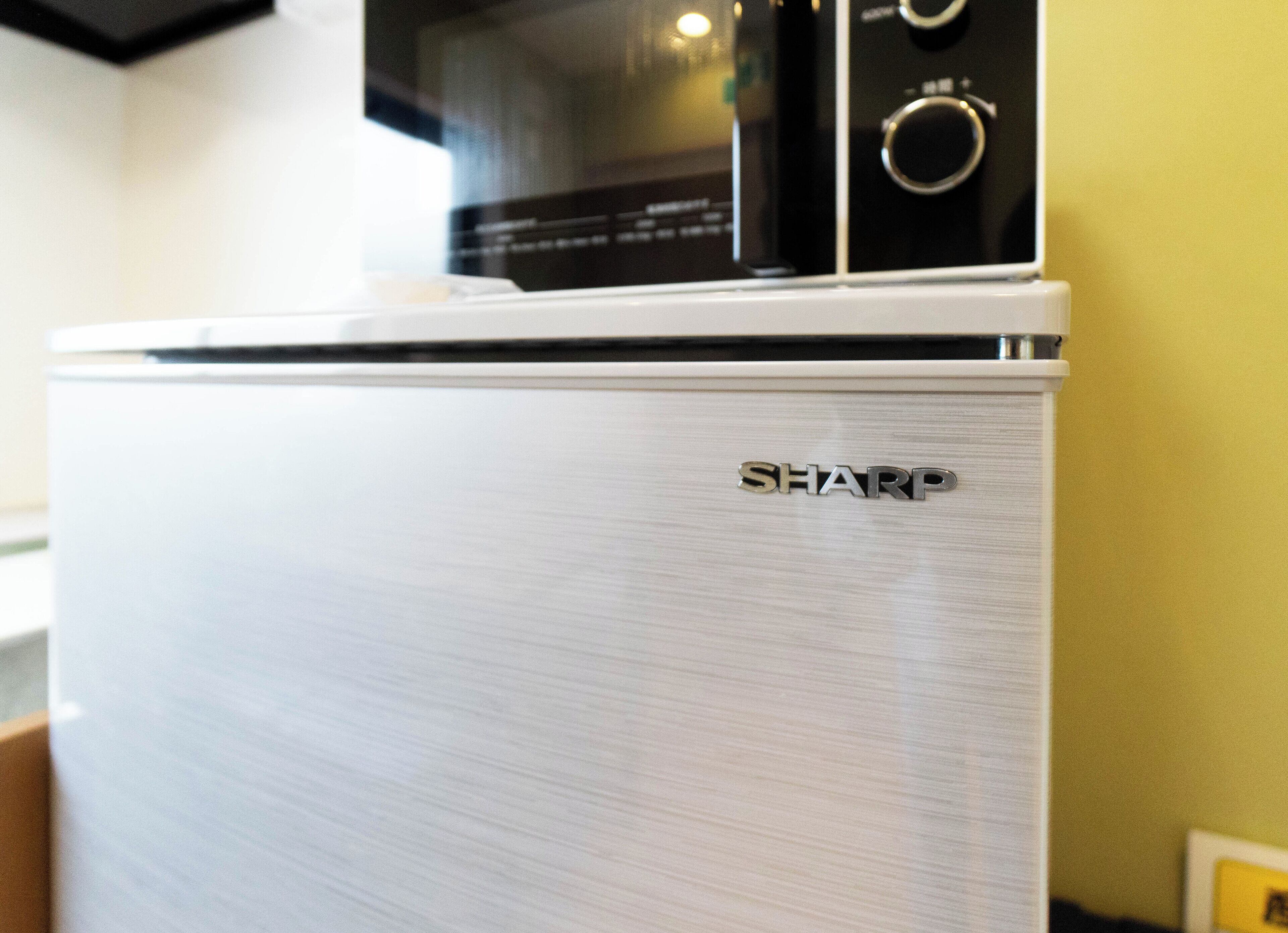 A kitchen with a white refrigerator and a microwave on top.