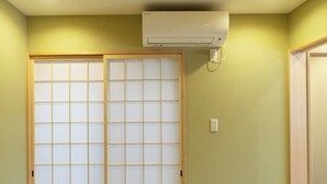 Una habitación con esteras de tatami, un puertas correderas tipo shoji y un equipo de aire acondicionado.