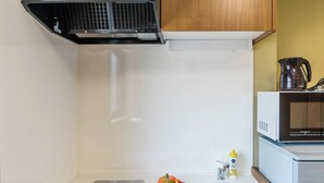 Una cocina compacta equipada con microondas, cafetera y lavamanos.