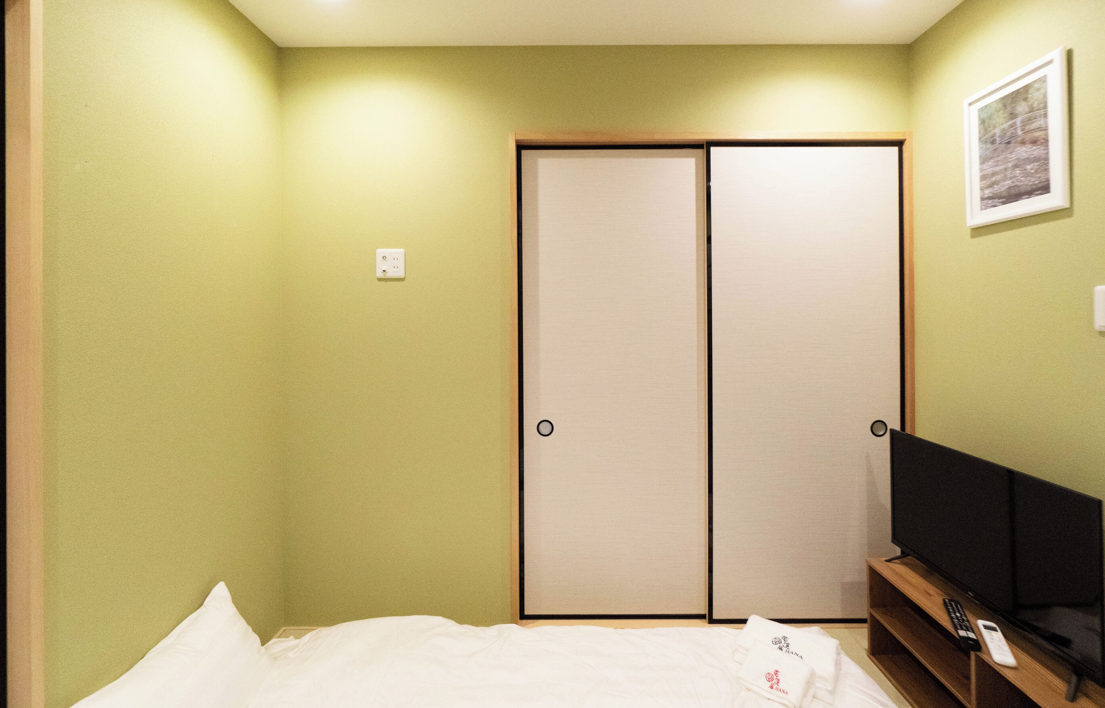 A hotel room with a bed, a television, and a sliding door closet.