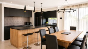 Una cocina moderna con armarios negros, una isla de madera y taburetes negros.