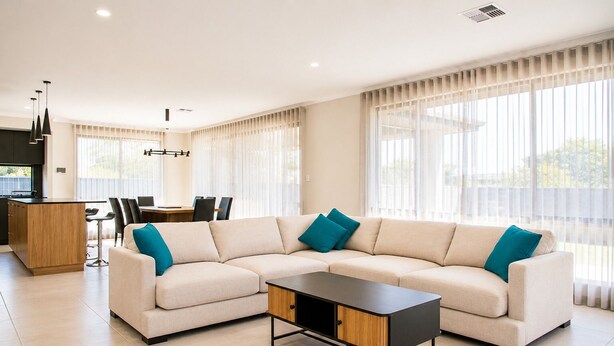 Una sala moderna con un sofá modular, una mesa de centro y un comedor con sillas.