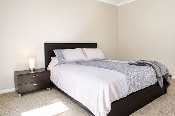 A bedroom with a bed, nightstand, and a bedside lamp.