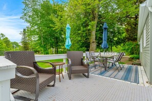 Un patio al aire libre con mobiliario de mimbre, una mesa y dos sombrillas.