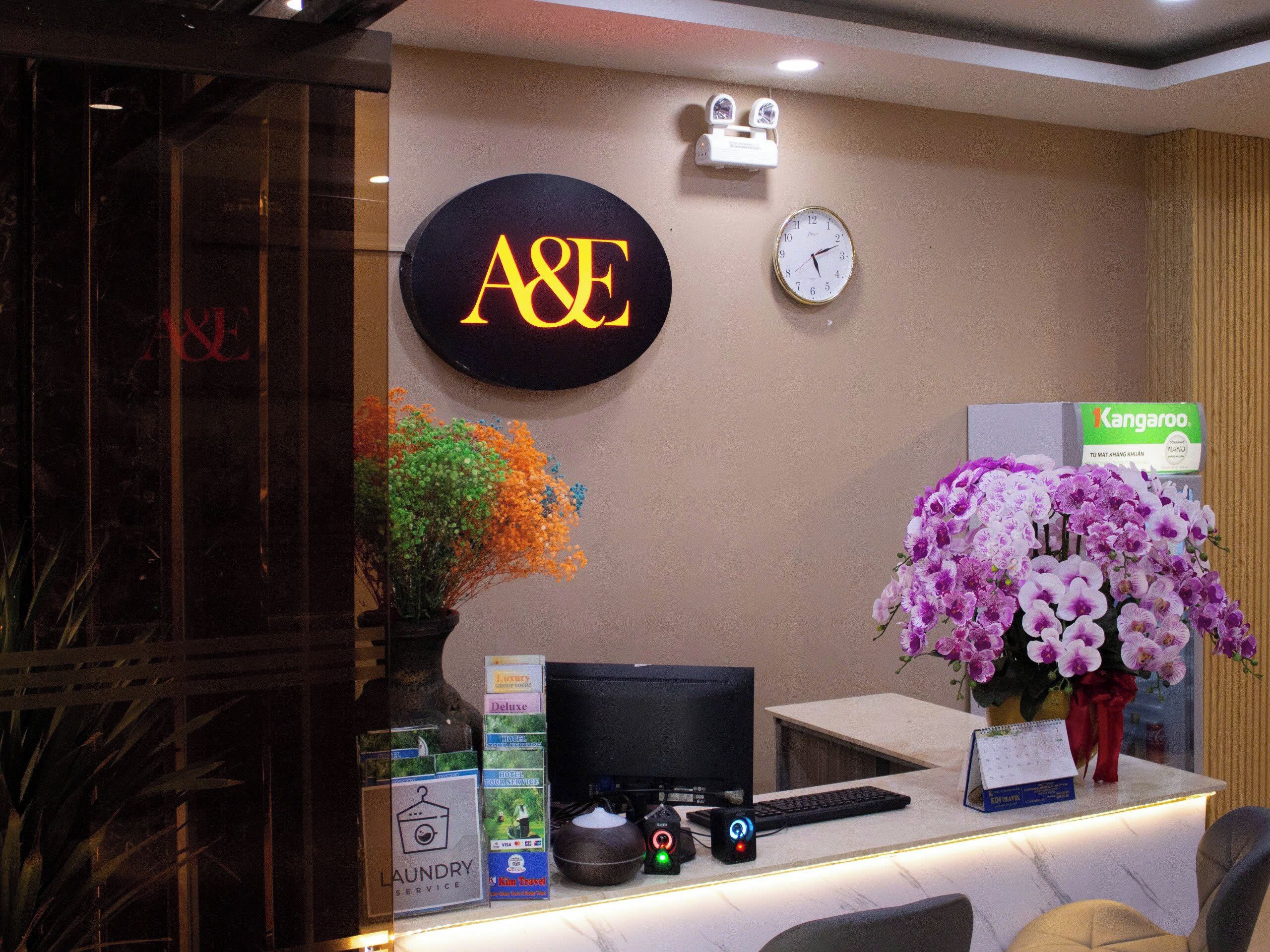 A reception desk with a clock, A&E sign, and a flower arrangement.