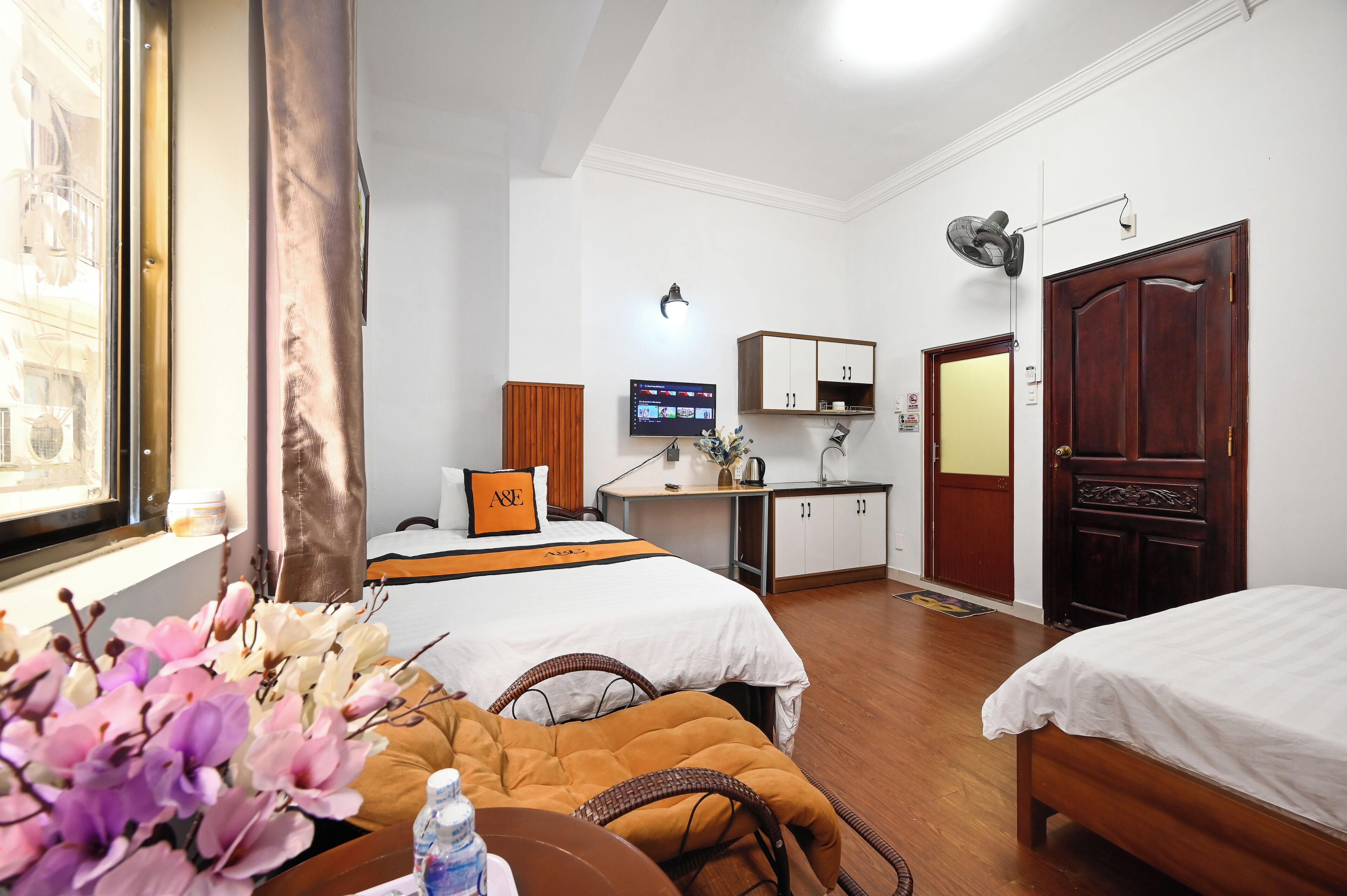 Ett hotellrum med två sängar, ett skrivbord, en TV, en garderob och ett fönster med gardiner.