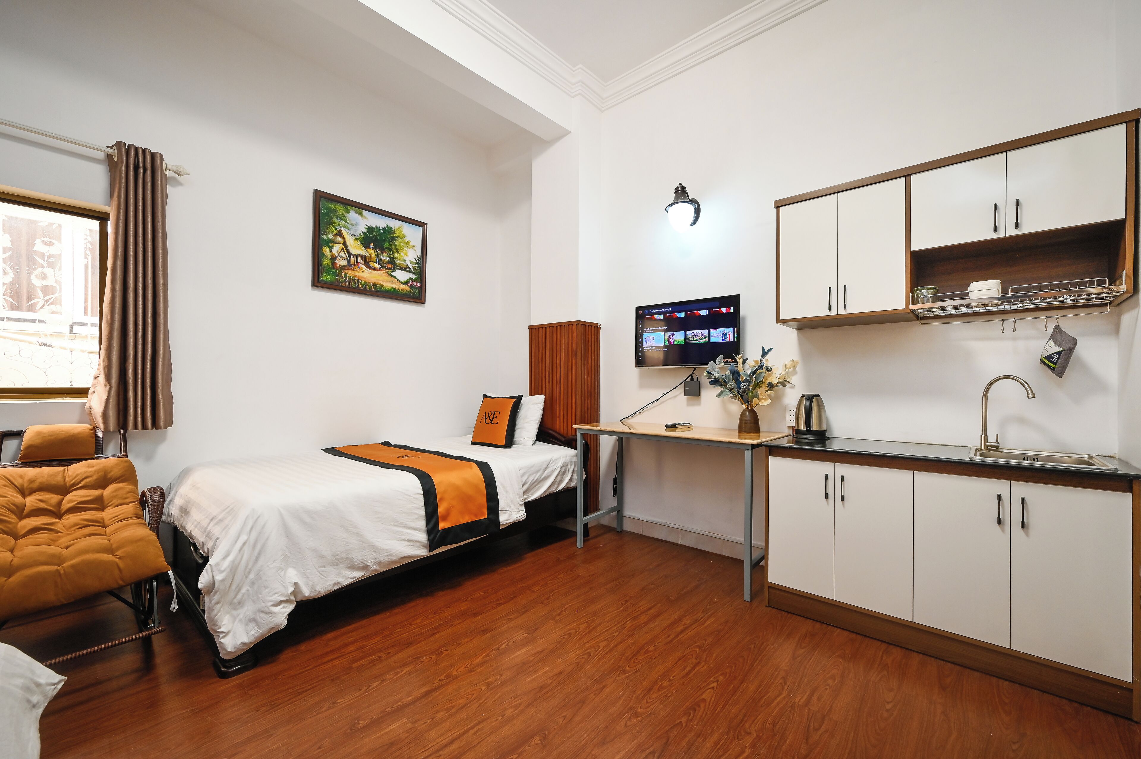 A hotel room with a bed, a desk with a computer, a sink, and a cabinet.