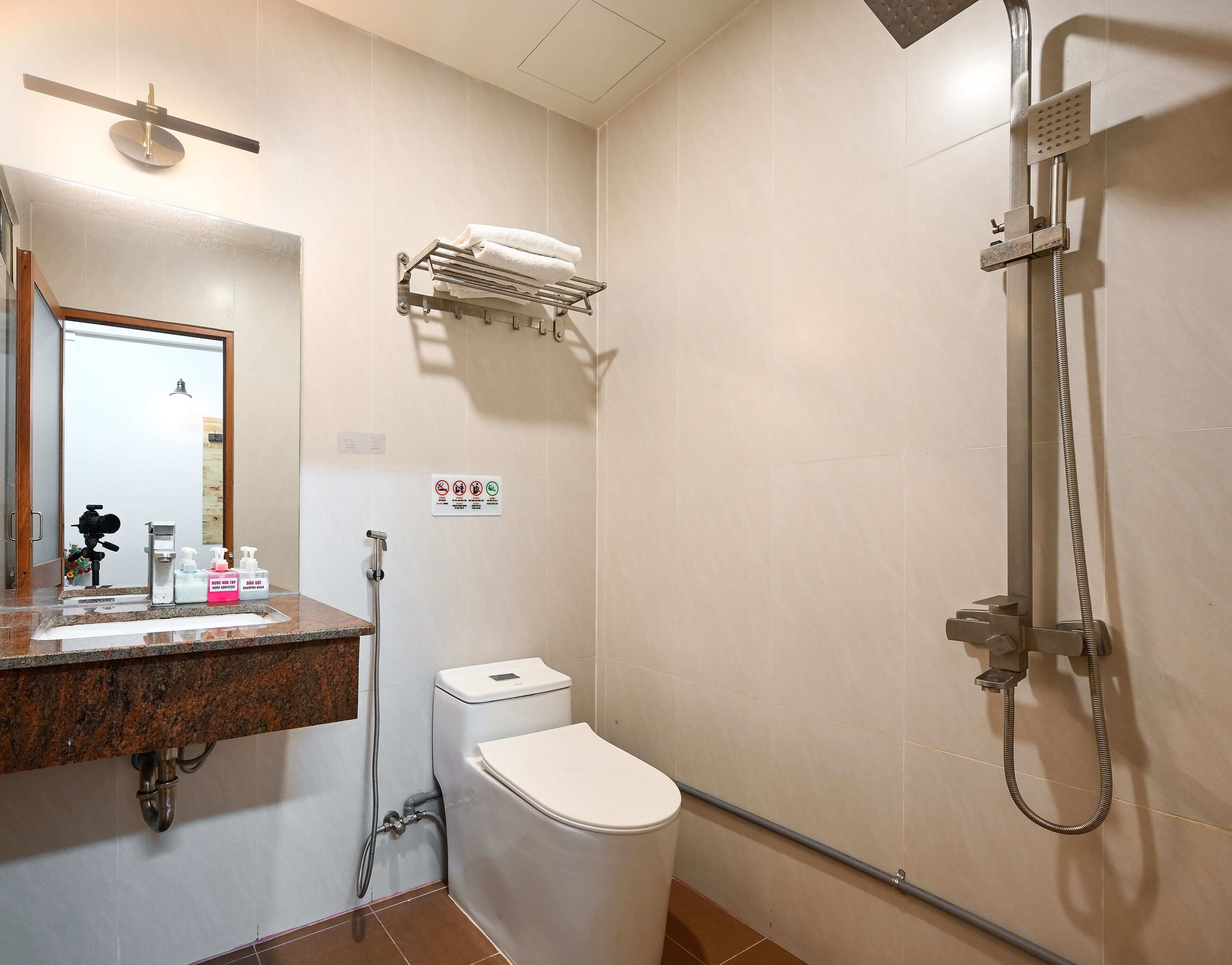 Egy modern fürőszoba, amelyben WC, mosdókagyló és zuhanyzó található.