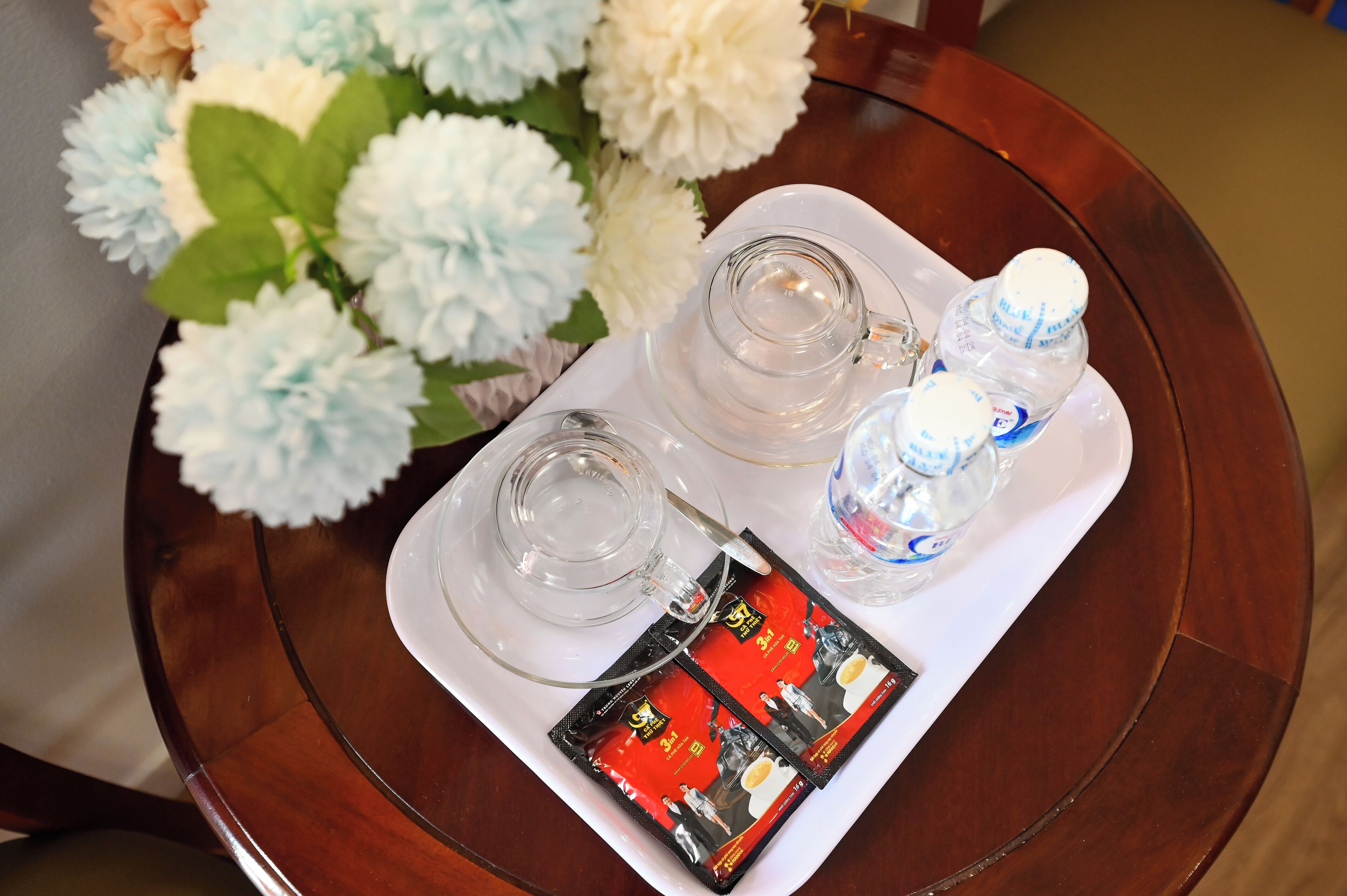Un plateau avec deux verres, deux bouteilles d’eau et un magazine, posé sur une table en bois.