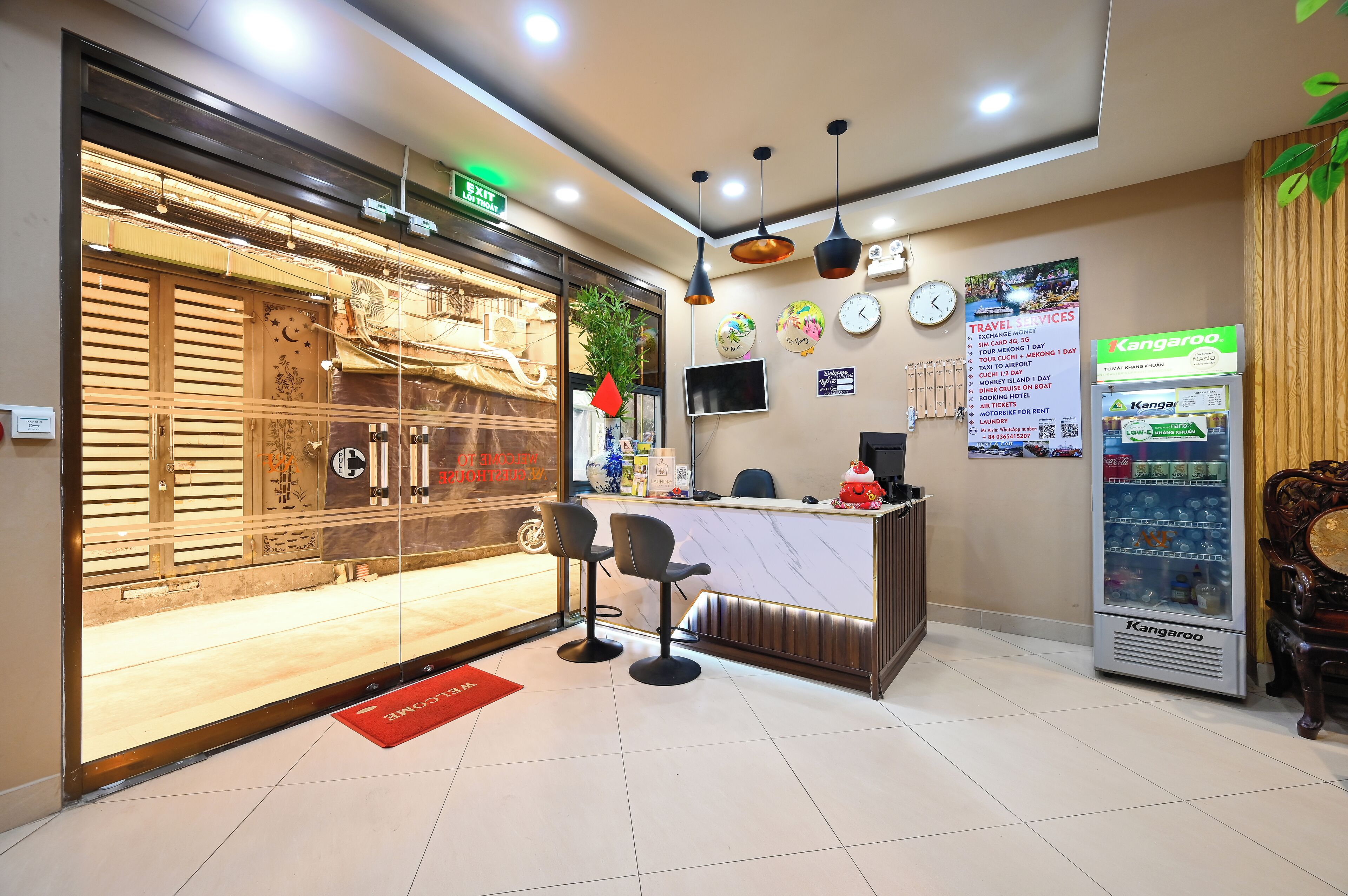A hotel reception area with a counter, two bar stools, a Kangaroo vending machine, and a clock on the wall.