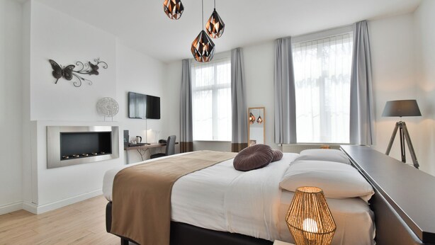 Een moderne hotelkamer met een groot bed, een bureau, een flatscreen televisie en een open haard.
