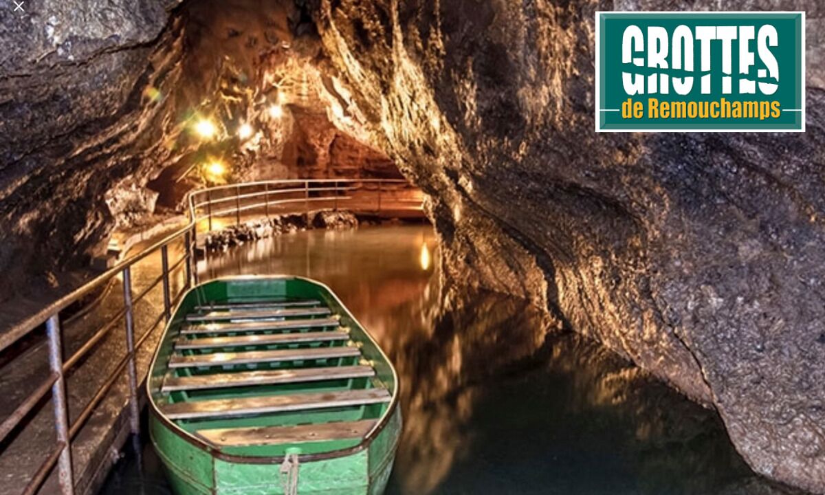 Una escalera verde que desciende hacia un cuerpo de agua dentro de una cueva, con barandales de metal.