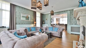 Een ruime woonkamer met een grote hoekbank, een salontafel en hanglampen.