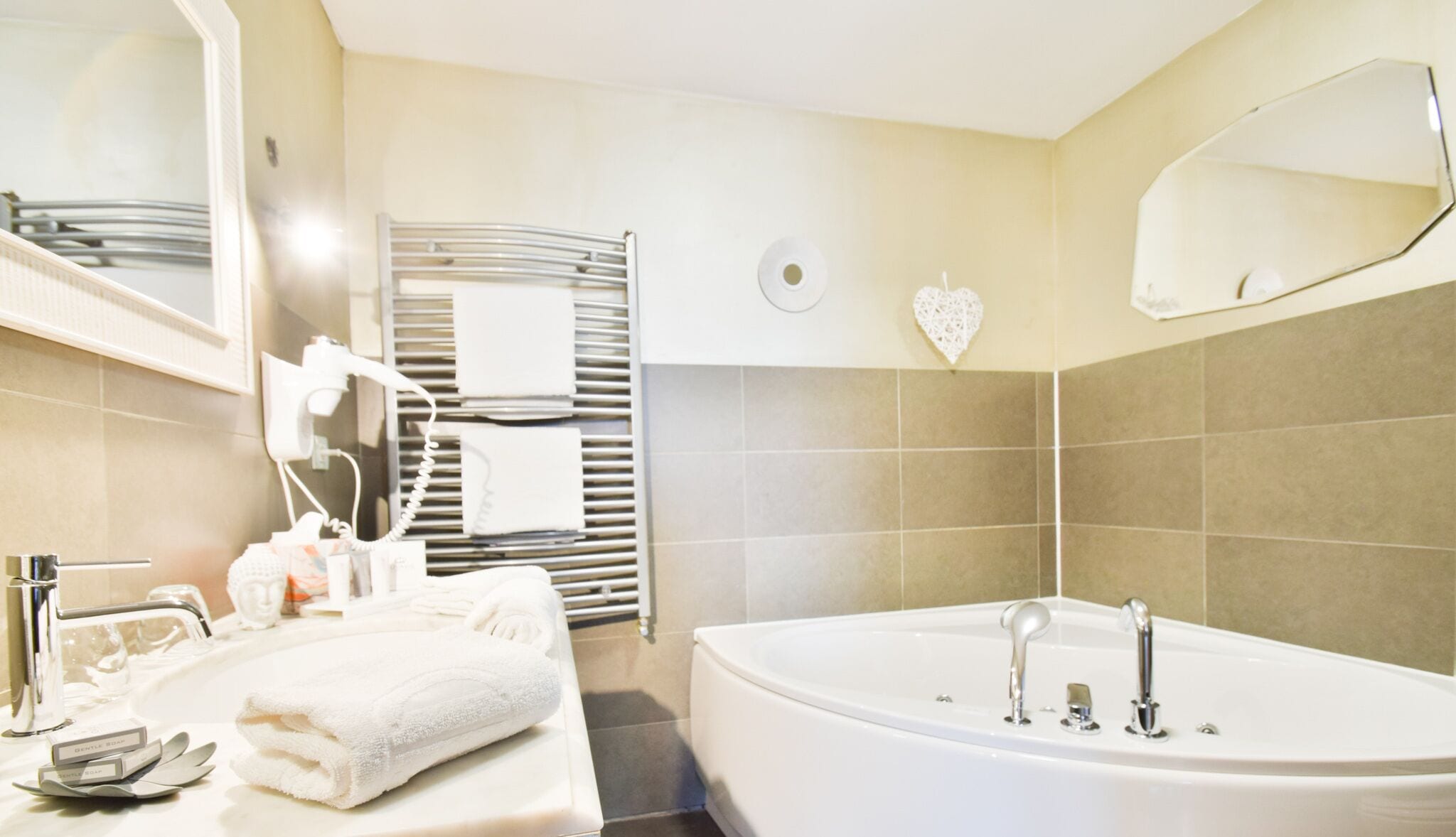 A modern bathroom with a large bathtub, a mirror, and a towel rack.