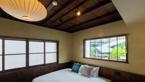A bedroom with a large bed, a window with a view of greenery, and a ceiling fan. - HOTEL RIN TOKYO (Tokyo)