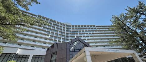 A multi-story hotel with a modern architectural design, featuring a prominent entrance with a glass facade.