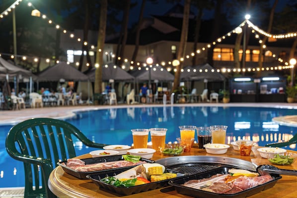 A poolside dining setup with a grill, various food items, and drinks. - Seagaia Forest Condominiums (Miyazaki)
