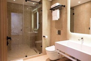 Une salle de bain moderne avec une douche à parois de verre, un lavabo blanc et des toilettes.