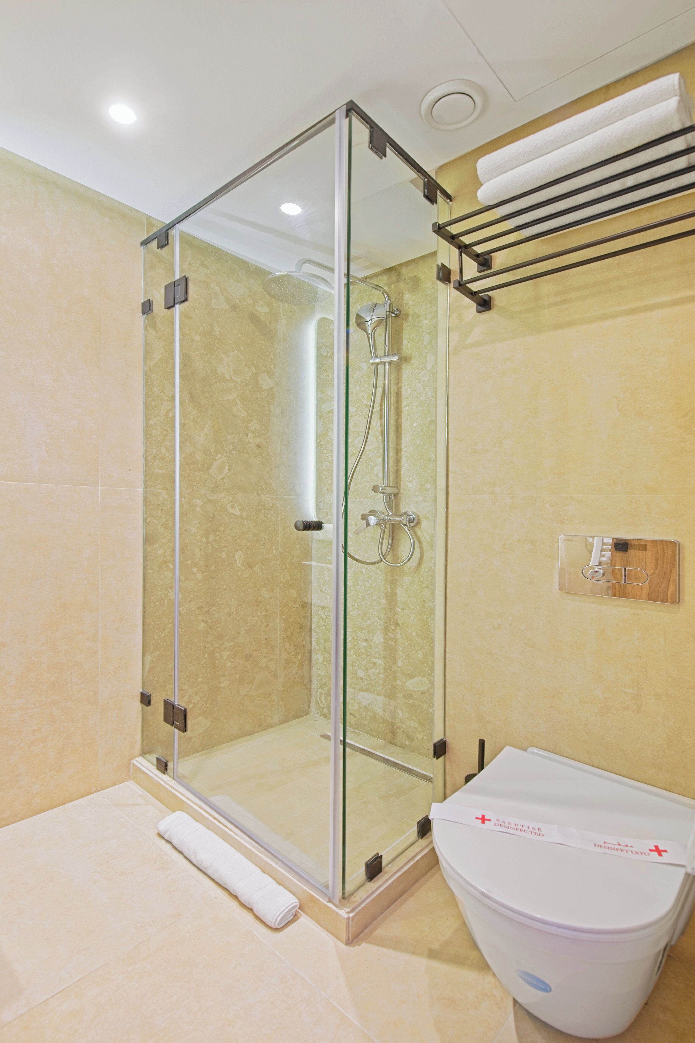 Une salle de bain moderne avec une douche à parois de verre, des toilettes blanches et un porte-serviettes.