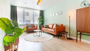 Ein modernes Wohnzimmer mit einer Couch, einem Couchtisch und einer großen Pflanze.