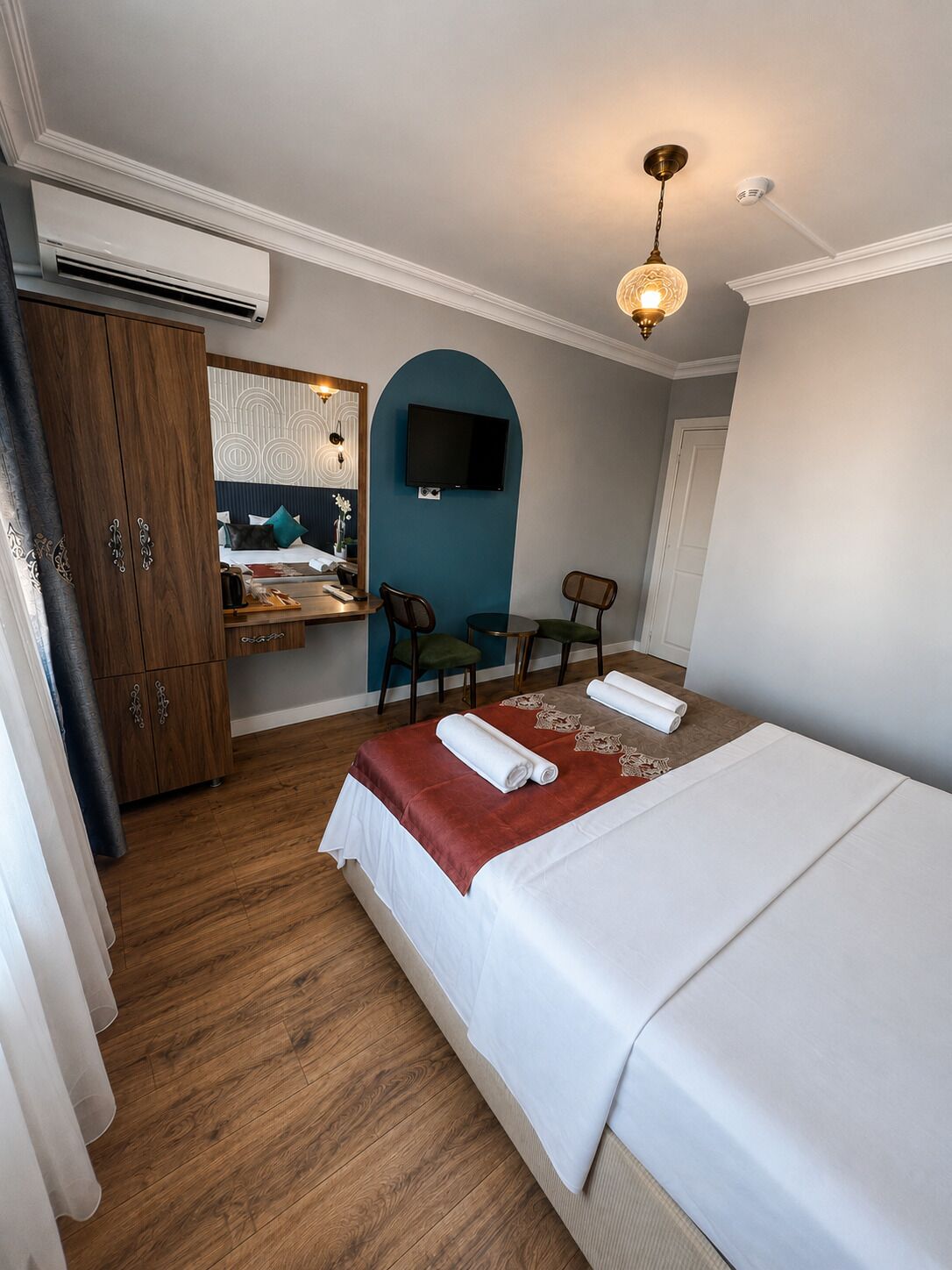 Une chambre d’hôtel comprenant un lit, un bureau avec une chaise, une télévision et une armoire.
