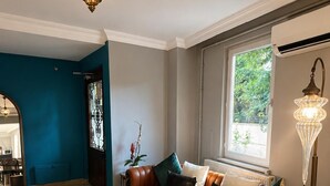 A living room with a brown leather sofa, a round coffee table, and a large window. - DeMaree (Istanbul)