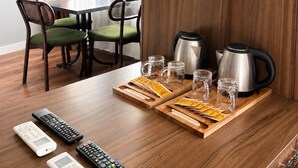 A hotel room with a wooden dining table, two chairs, a coffee maker, and a remote control on the table. - DeMaree (Istanbul)