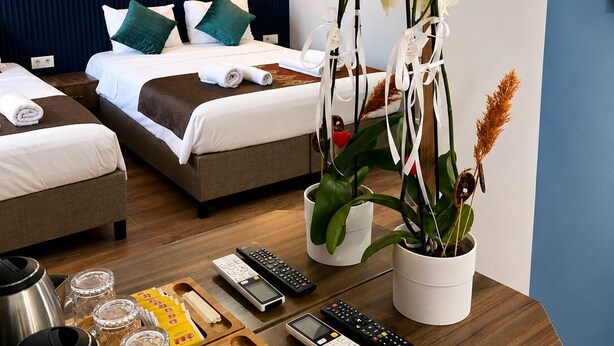 A hotel room with two beds, a dining table with remote controls, a kettle, and a tray of snacks. - DeMaree (Istanbul)