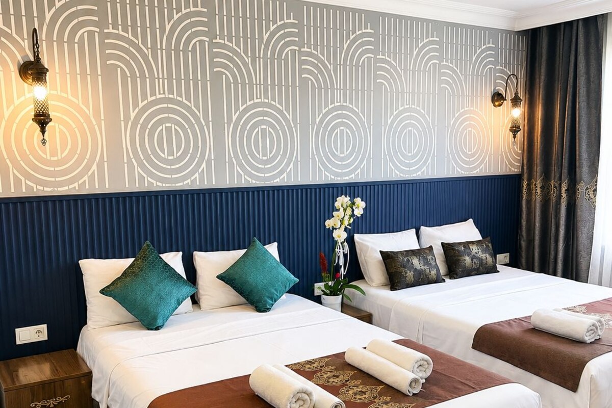 Habitación de hotel con dos camas, un adorno en la pared y una mesita de noche.